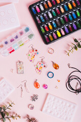 Earrings, pendants and rings made of epoxy resin, mold and sparkles on a pink top and vertical view
