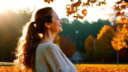 Elderly smiling woman is sitting on a bench in autumn park. Concept of happiness and relaxation