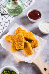 Fried chicken nuggets on a board and ketchup in a bowl on the table vertical view