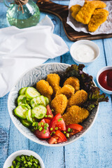 Fried chicken nuggets, cucumber and tomato in a bowl on the table vertical view