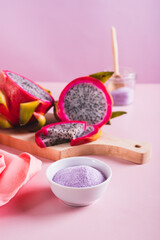 Pink matcha powder in a bowl and fresh dragon fruit on the table vertical view