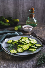 Fresh sliced ​​cucumbers and dill on a plate on the table vertical view