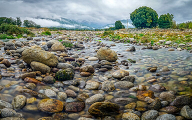A low-flowing river with banks full of round stones