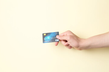 Man holding credit card on pale yellow background, closeup