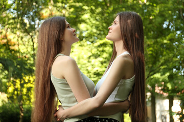 Fototapeta premium Two beautiful twin sisters spending time together in park