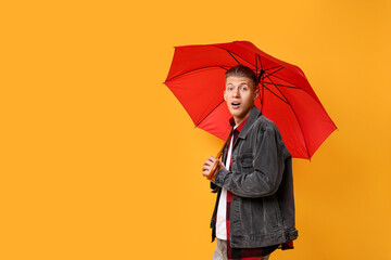 Young man with red umbrella on yellow background, space for text