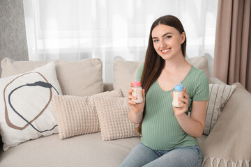 Expecting twins. Pregnant woman holding two bottles of milk at home, space for text