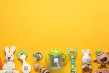 Different baby rattles on yellow background, flat lay. Space for text