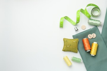 Flat lay composition with different sewing supplies on white background. Space for text