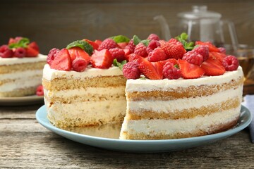 Tasty sponge cake with fresh berries and mint on wooden table, closeup