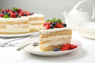 Tasty sponge cake with fresh berries and mint served on white table