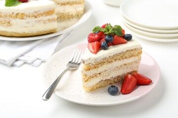 Tasty sponge cake with fresh berries and mint served on white table, closeup
