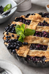 Delicious Homemade Blueberry Pie with mint on gray table with plates and cutlery close up