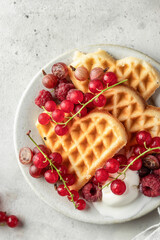 Homemade waffles with summer berries and a scoop of ice cream in plate on grey table close up. Heart shaped waffles