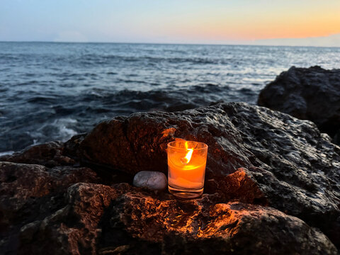 Burning candle on the beach of sea shore at sunset