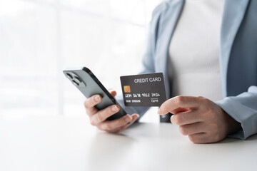 A person using a smartphone while holding a credit card. Ideal for concepts related to finance, shopping, and online transactions.