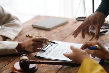 Professionals discussing a legal document in an office setting with a gavel on the table, symbolizing law and agreement.