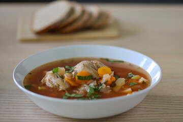 Homemade chicken and vegetable soup on wooden table.