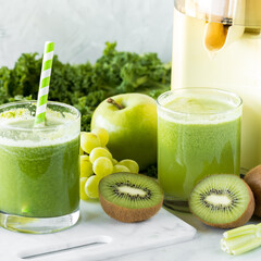 Preparing fresh homemade green juice with ingredients all around.