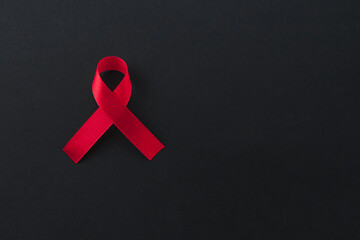 Red awareness ribbon on black background, top view. Space for text