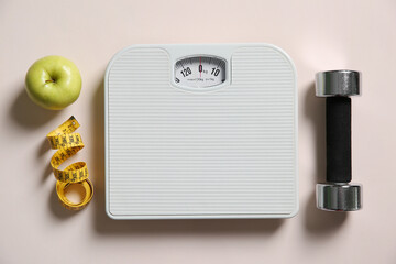 Scale, measuring tape, dumbbells and fresh apple on beige background, flat lay