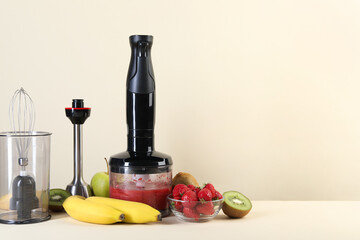 Hand blender kit, mixture of ingredients and fresh fruits on beige background, space for text
