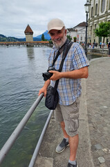 Mature man with camera on the embankment of the river Reuss in the city of Lucerne