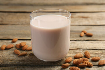 Glass of almond milk and almonds on wooden table