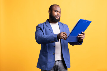 Man working accounting job browsing though financial report pages, studio background. Worker reading paperwork containing economic graphs and figures, solving bookkeeping tasks