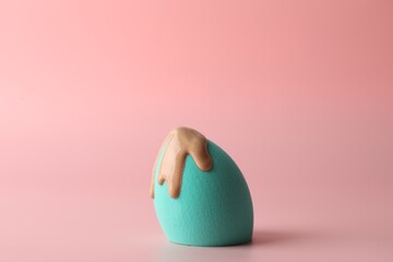 Makeup sponge with skin foundation on pink background
