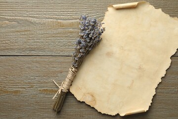 Sheet of old parchment paper and lavender flowers on wooden table, top view. Space for text