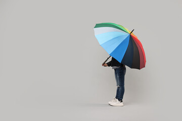 Little girl with colorful umbrella on light grey background. Space for text