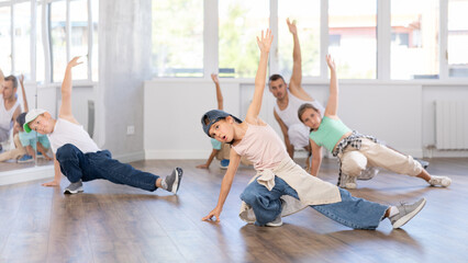 Fototapeta premium Concetrated preteen boys and girls studying movement of contemporary dance in classroom with his friends