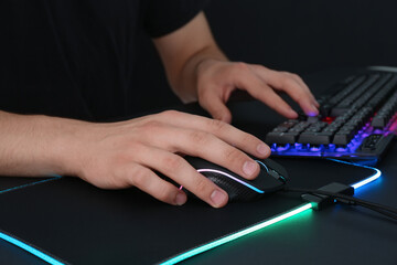 Gamer using modern wired computer mouse at black table, closeup