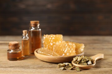 Natural honey tincture, propolis granules and sweet honeycombs on wooden table