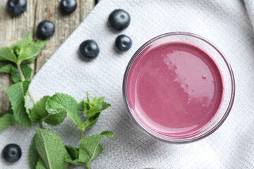 Tasty fresh acai juice in glass with berries and mint on table, flat lay