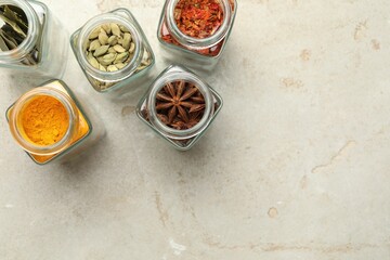 Different spices in glass jars on light grey table, flat lay. Space for text