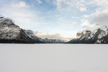 Vermillion Lake, Banff National Park frozen during winter. Light blue sky with sun beginning to set, casting a slight pink/orange hue across the sky.
