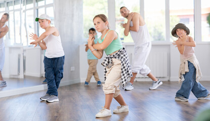 Fototapeta premium Young boys and girls in casual wear performing hip hop at group dance class in choreographic studio