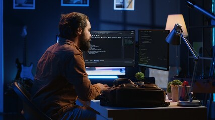 Freelancing software programmer arriving in personal office at home, resuming work on coding. Self...
