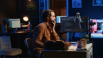 Freelancing system administrator arriving in personal office at home, resuming work on coding. IT...