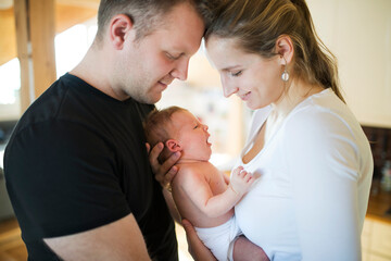 Fototapeta premium New parents holding newborn baby girl. Unconditional paternal love, idyllic family moment.