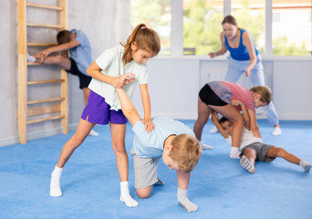 Obraz premium Kids in sportswear exercising self-protection techniques in pair during class at gym
