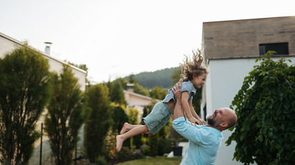 Father throwing little son up in the air in the garden. Dad with kid having fun outdoors. Father's...