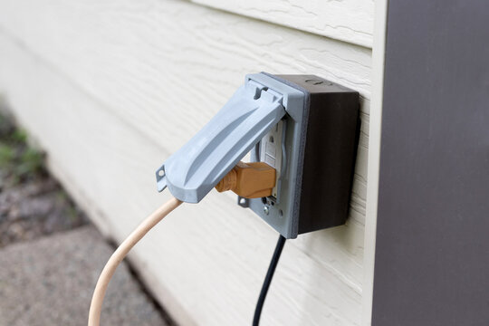 Outdoor electrical outlet. Power cord plugged into an outdoor outlet