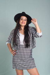 Portrait of calm beautiful young woman standing in studio wearing black hat and posing for photo.