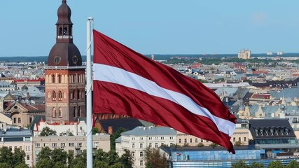 Latvian national flag waving with old Riga cityscape in the background
