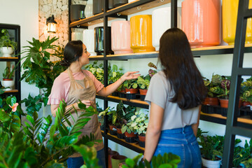 Worker advising customer in cozy plant shop, creating friendly shopping experience with lush...