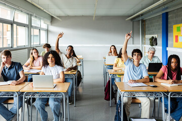 Young students raising hands to ask a question during lecture at high school classroom. Education and back to school concept.