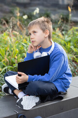 Thoughtful boy student with earphones and exercise book